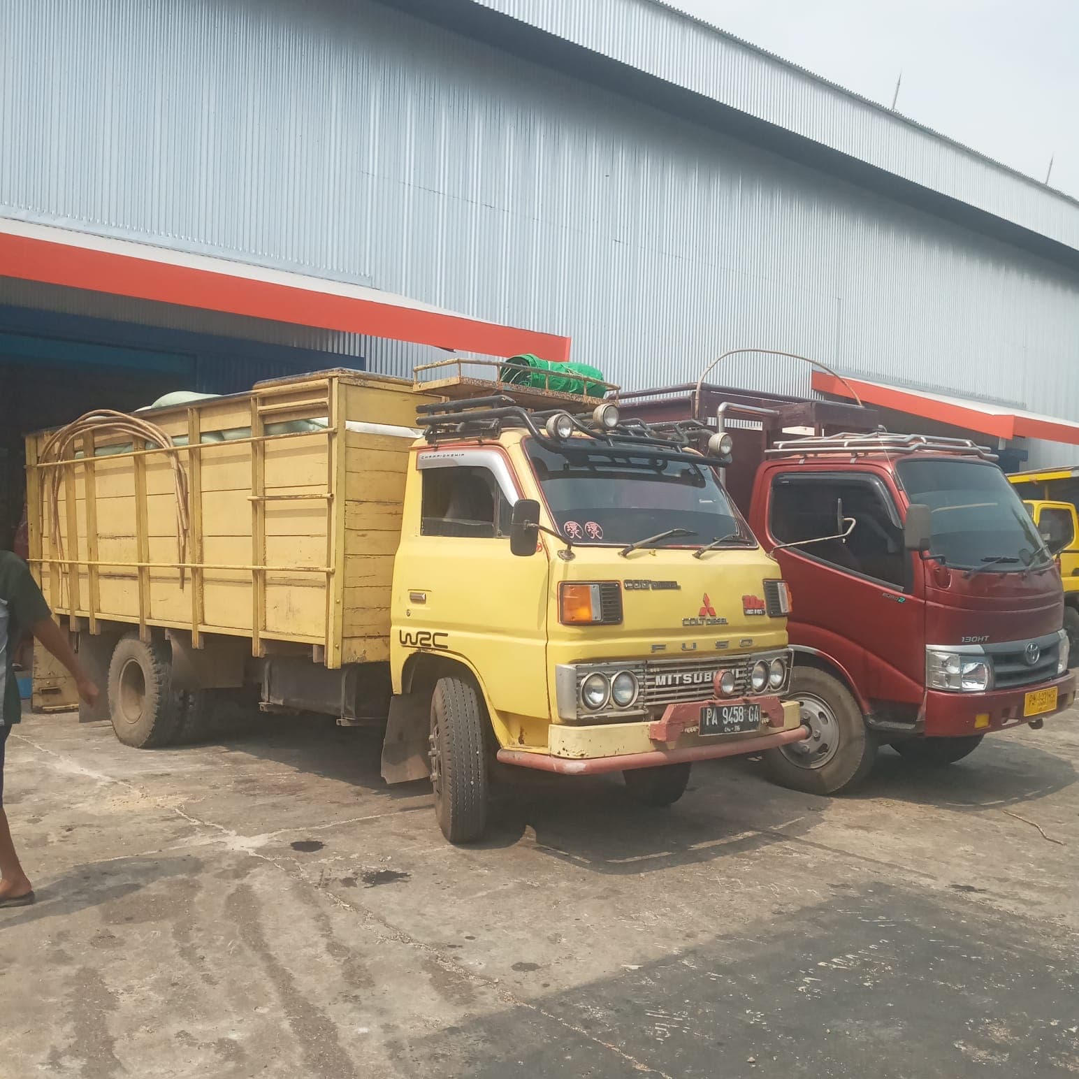 Dua truk angkutan barang berada di area gudang