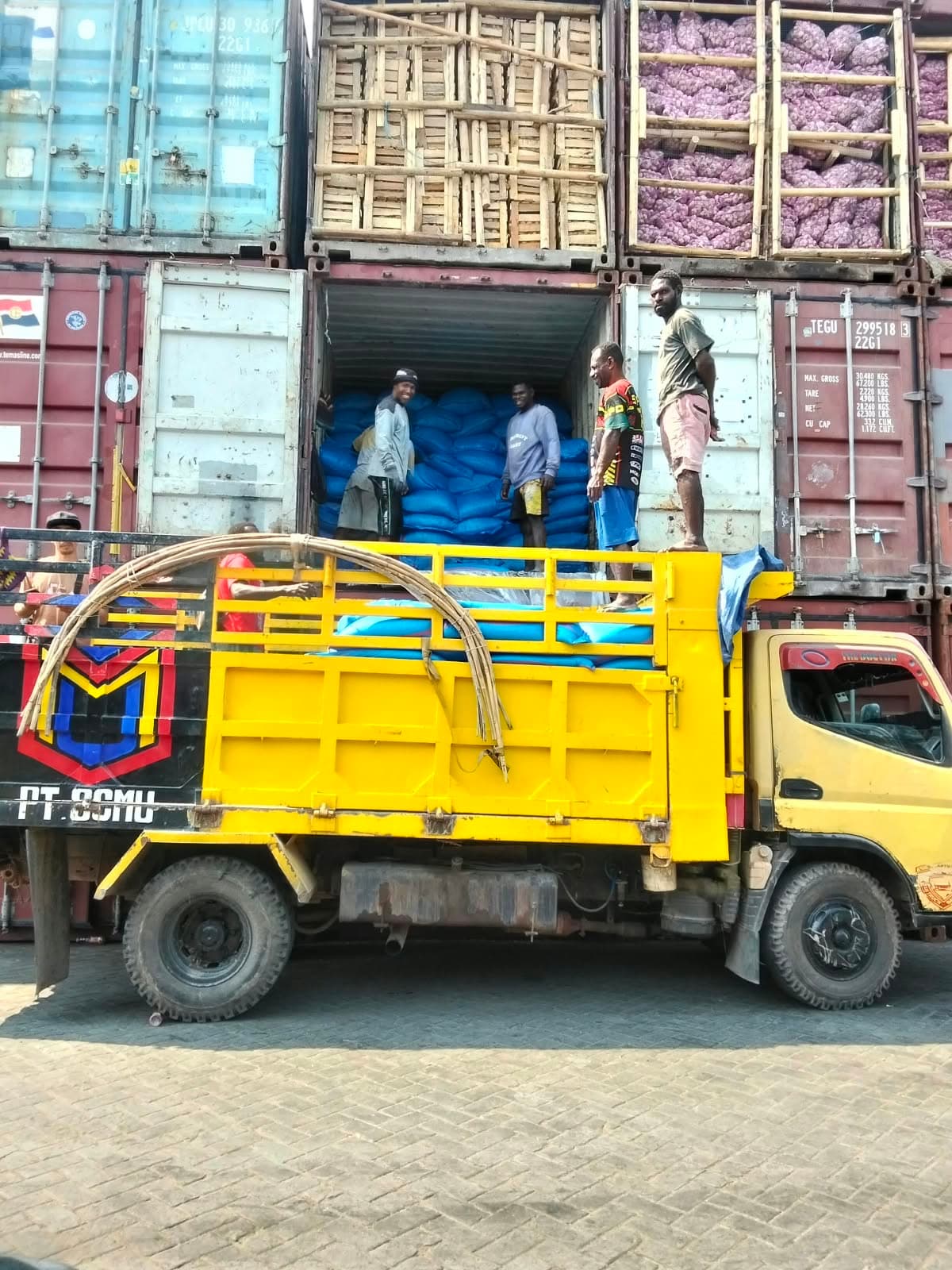 Pekerja memindahkan muatan dari kontainer ke truk