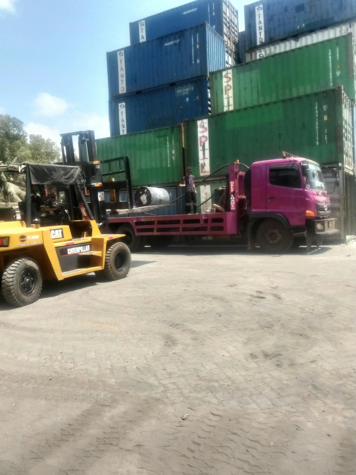 Forklift dan truk SCMU menangani drum di area kontainer