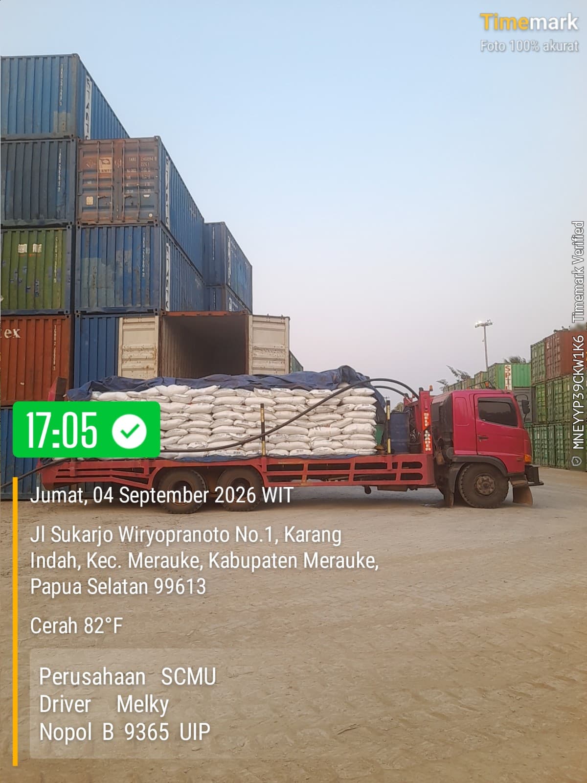 Truk SCMU menerima muatan karung di antara susunan kontainer
