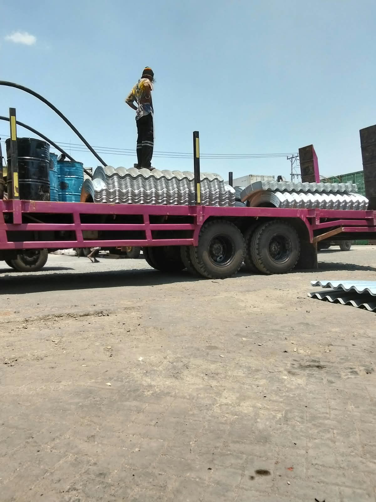 Pekerja memeriksa susunan material baja bergelombang di atas truk