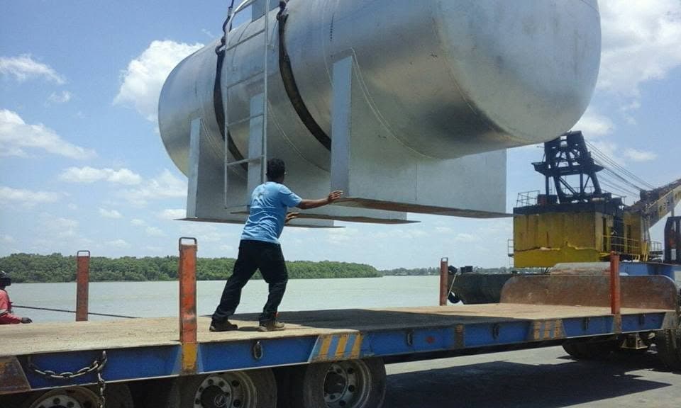 Muatan tangki berukuran besar berada di atas trailer dekat perairan
