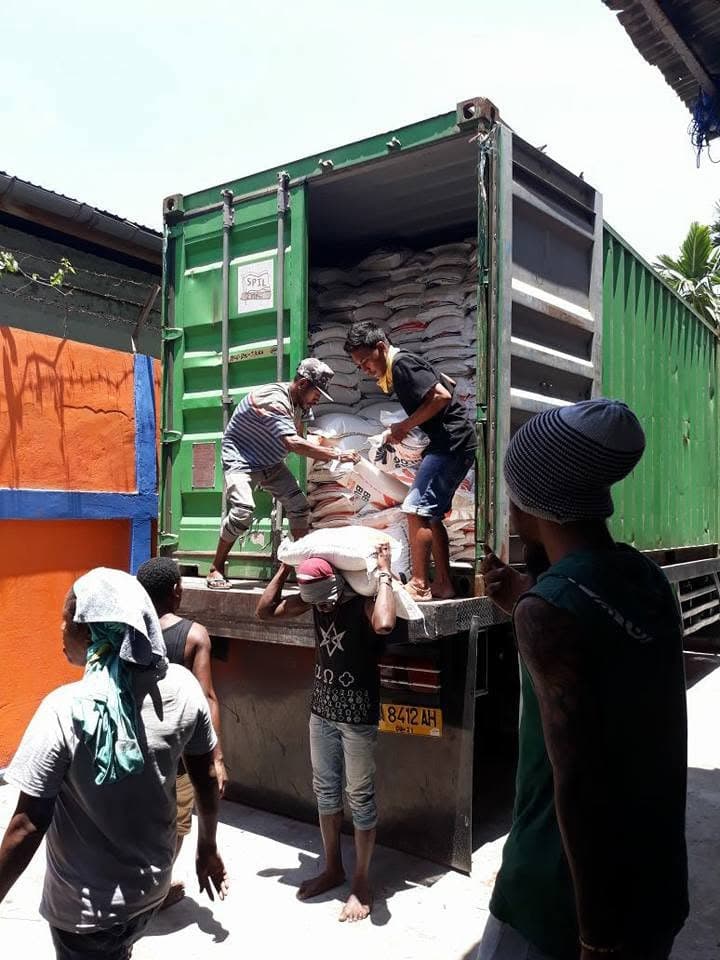 Pekerja menurunkan karung dari kontainer ke kendaraan angkut